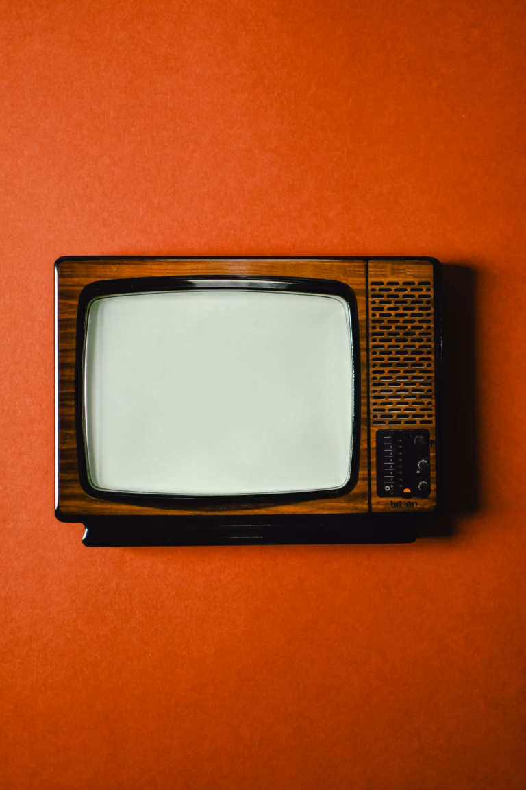 Retro television set with a wooden finish on a vivid orange background, showcasing classic design.